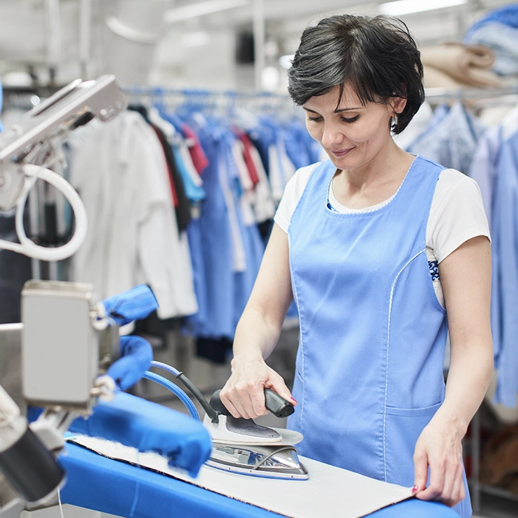 Imagen de mujer realizando la plancha en lavanderia profesional para la entrada de setiembre, Lavado y proteccion de tejidos.